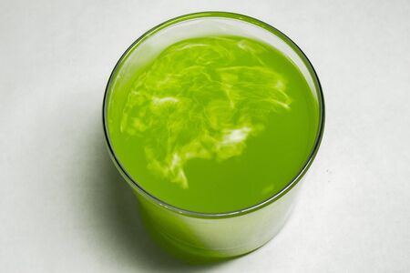 Glass with green liquid placed on a tableの写真素材