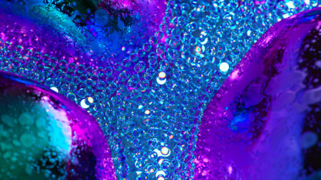 Abstract concept. A stream of glowing blue neon particles flows around gray metal bubbles. Close-up....