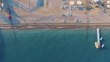 Top view of the coastline. Sea and sandy beach. Sunny day. Pier in the sea. Sun loungers and umbrellas on the beach. High quality photoの写真素材