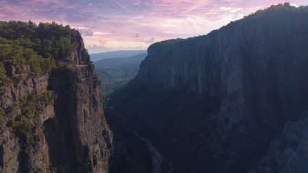 Aerial drone view of a large deep canyon. Sheer cliffs and green trees. Wildlife concept. Sunset...