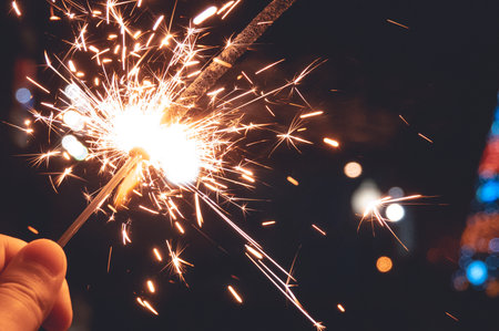 Bengal fire in hand, sparkling and colorful Christmas bokeh, new year.