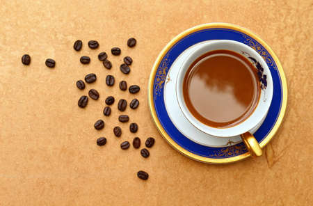 Coffee cup on old brown retro background with roasted coffee beans.の写真素材