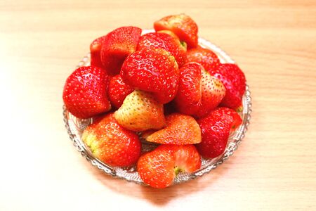 Sliced strawberries in glass dish on wooden table.の写真素材
