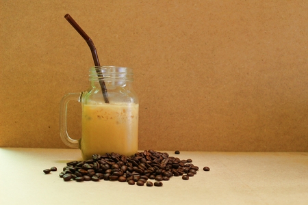 Mug of iced coffee on brown background and roasted coffee beans.の写真素材