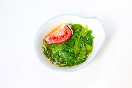 Melientha suavis soup decorated with a piece of fresh red tomato on top in beautiful bowl on white background.の写真素材