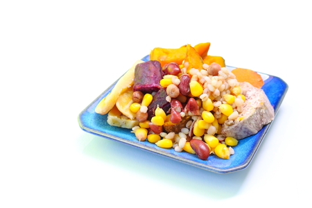 Boiled mix cereals corn, cultivated banana, barley, taro, peanut, sweet potato, yam, pumpkin and red kidney bean on beautiful blue dish with copy space on left.の写真素材