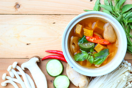 Thai spicy mixed vegetales soup with mixed mushrooms on wooden background, local Thai food.