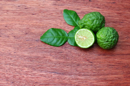Fresh whole and half kaffir limes on wooden background with copy space.の写真素材