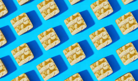 Sliced Caramel Peanut Chocolate on Blue Background with same shadows. Abstract Food Background in...
