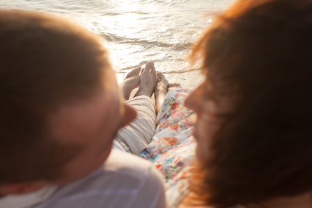 Closeup of couples feet on the water on the beach. Romantic shot on the sunsetの写真素材