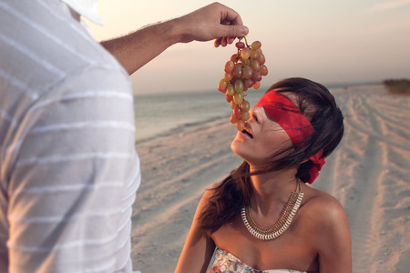 Boyfriend feeding a grapes her girlfriend on the beach romantic dateの写真素材