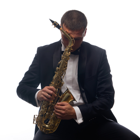 Isolated portrait of sitting saxophonist in tuxedoの写真素材