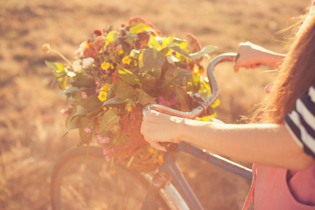 Girls arms holding an old bike handlebar with flowers basketの写真素材