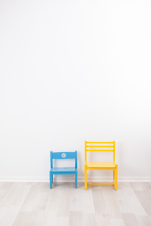 Two vintage child chairs on white wallの写真素材
