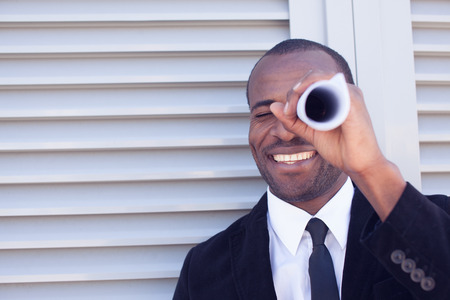 black man searching thru paper spyglassの写真素材