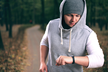 Yong man using fitness bracelet during morning runの写真素材