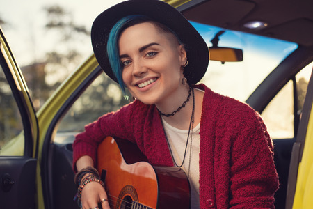 Closeup face portrait of folk singer with guitar in car outdoorsの写真素材