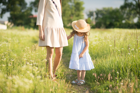 Stylish young mother with toddler girl walking on natureの写真素材