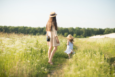 Stylish young mother with toddler girl walking on natureの写真素材