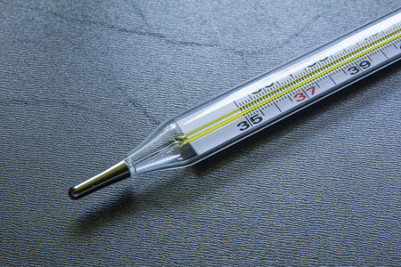 medical glass mercury thermometer on a black steel background