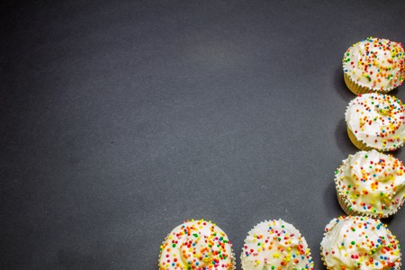 Colorful sweet cupcake with cream on black backgroundの写真素材