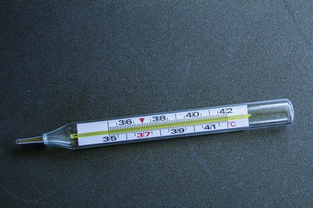 medical glass mercury thermometer on a black steel background