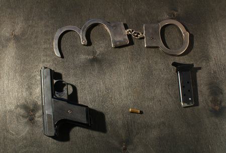 gun and handcuffs on black wooden backgroundの写真素材