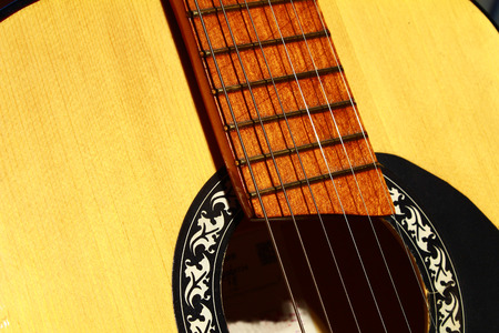 Wooden yellow acoustic guitar with metal strings close up