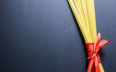 Yellow long spaghetti with red ribbon on black background.の写真素材