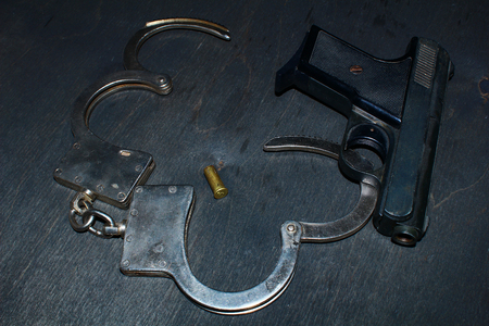 gun and handcuffs on black wooden backgroundの写真素材