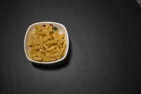macaroni pasta in plate on black background