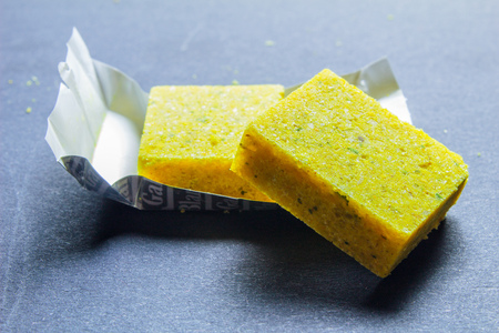Dehydrated bouillon stock cube salty meat and vegetables aromatic yellow spice, ingredient single whole condiment portion wrapped, open in paper packの写真素材