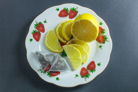 sliced lemon in a plate with tea bag on a gray backgroundの写真素材