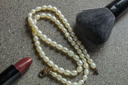 pearl necklace, lipstick and make-up brush on gray backgroundの写真素材
