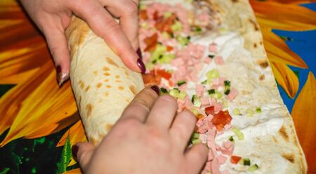 roll cooking sliced cucumber, sausage, tomato on pita, blur backgroundの写真素材
