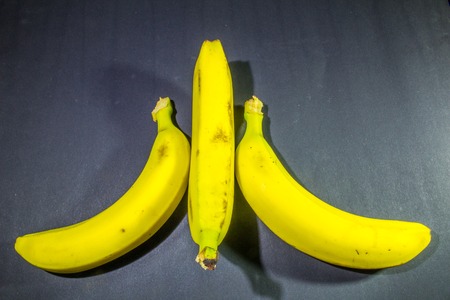 three mature bananas on dark gray backgroundの写真素材