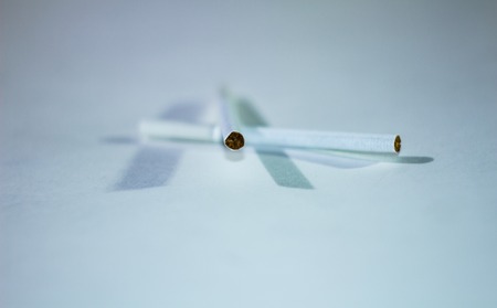 Two thin cigarettes on a white background