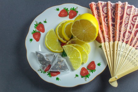 sliced lemon in a plate with tea bag on a gray backgroundの写真素材