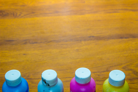 Colorful paint bottles on wooden background