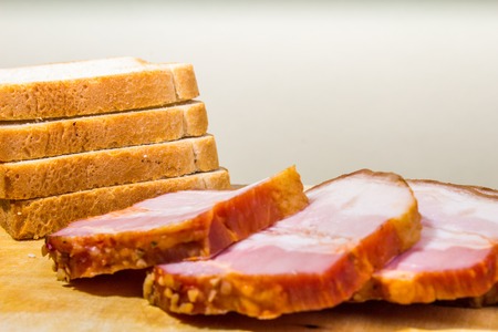 Raw smoked bacon slices with bread on wooden boardの写真素材