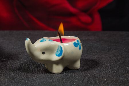 Candle-elephant on a dark background with a roseの写真素材