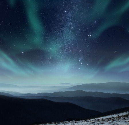 Starry night sky with aurora polaris over the mountainsの写真素材