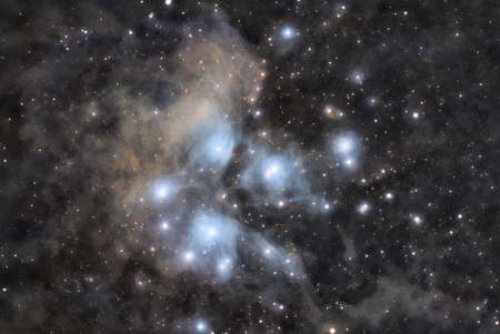 Astronomical image of the Pleiades star cluster surrounded by nebular cloudsの写真素材