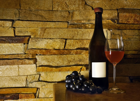 A picture of a red wine bottle with a glass and bunch of grapes.の写真素材