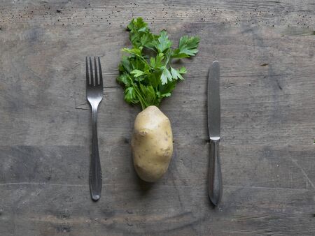 Fork, knife and potato on wooden background.の写真素材