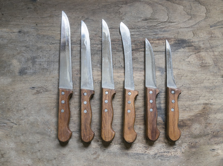 Six sharp knives on old , rustic wooden table.の写真素材