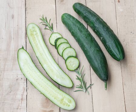 Fresh and ripped cucumbers decorated with rosemary on wooden desk.の写真素材