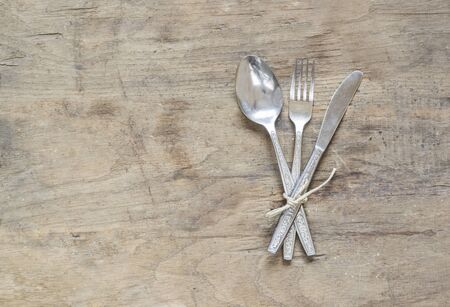 Silver, spoon, fork and knife on old, rusty, wooden background.