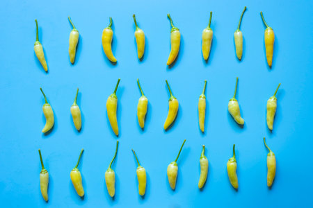 Pattern of small yellow hot peppers on light blue background