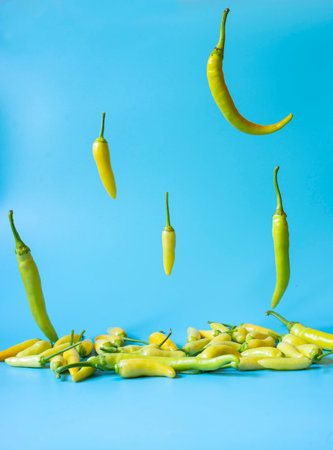 Green peppers falling on light blue background.の写真素材